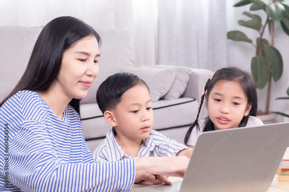 Asian single mother teaching homework for two kids at home, homeschool learning lifestyle use modern technology laptop or watching lesson and participating online with teacher, multitasking motherhood Asian single mother teaching homework for two kids at home, homeschool learning lifestyle use modern technology laptop or watching lesson and participating online with teacher, multitasking motherhood