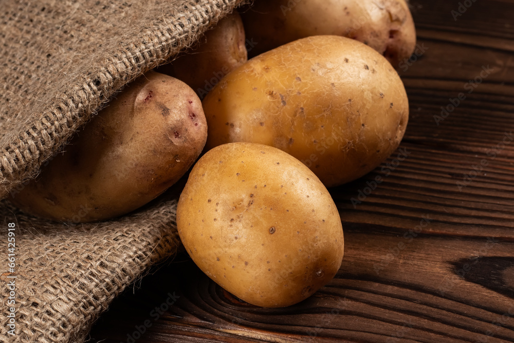 Raw potato food. Fresh potatoes in an old sack on wooden background