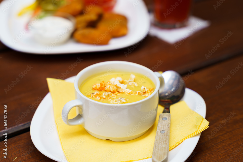 Bowl of sweet corn soup with popcorn on a wooden table Bowl of sweet corn soup with popcorn on a wooden table