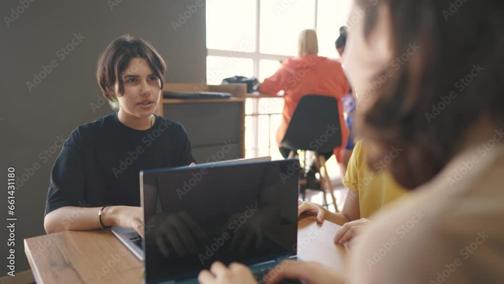 a group of students sit in a cafe and do a project on a laptop together. business lifestyle concept of modern training and development. students discuss their homework and eat fast food burgers