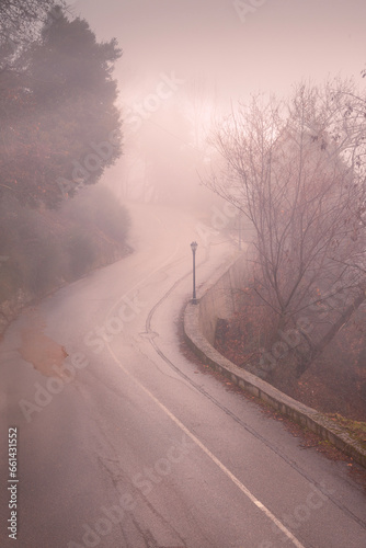 Dreamy road curvature with ethereal light and low morning fog, in the mountainous region of Agrafa, in central Greece, Europe.