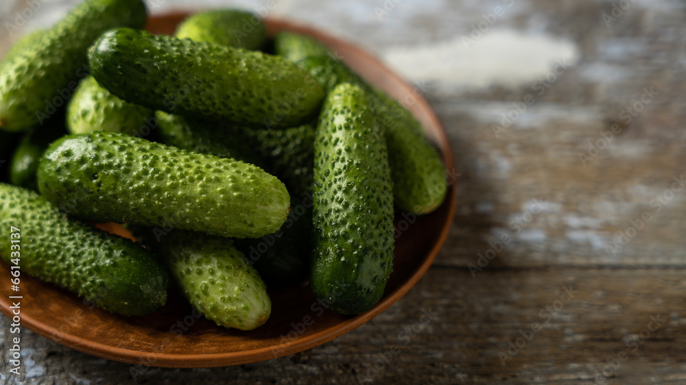 Green cucumbers on a plate, old wooden background, banner, space for text Green cucumbers on a plate, old wooden background, banner, space for text