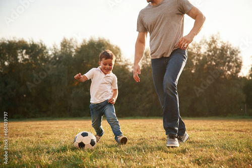 Playing soccer. Father and little son are having fun outdoors