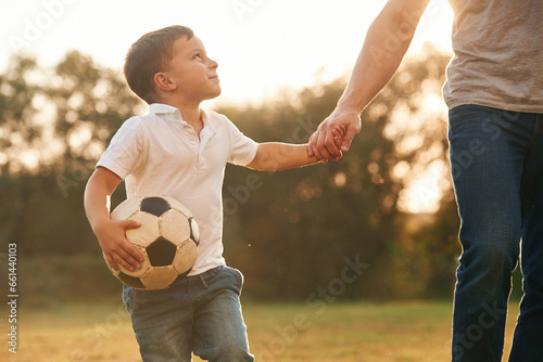 Holding hands and soccer ball. Father and little son are playing and having fun outdoors © standret