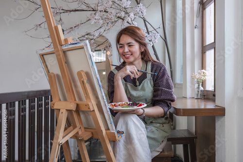 Young female artist works on abstract acrylic painting on canvas in art painting studio.