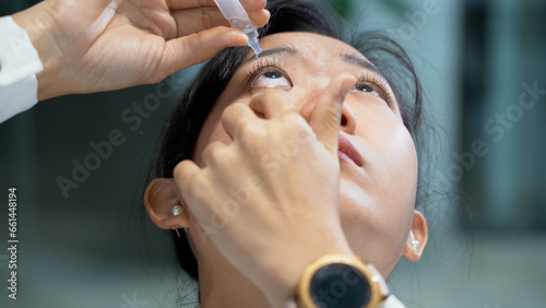 asian business woman feels eye fatigue or dry eye uses eye drops while long working with laptop computer office.