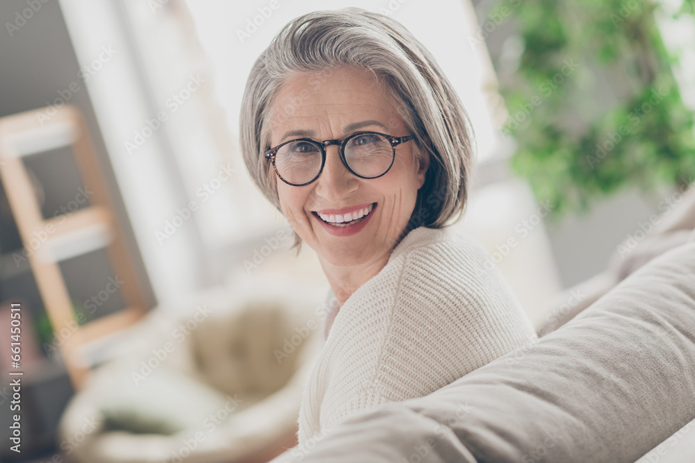 Fototapeta premium Photo of adorable pretty senior lady dressed white cardigan eyewear smiling indoors house room