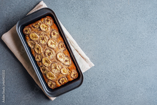 Delicious freshly baked homemade banana bread cake with no gluten and sugar free, top view on gray concrete background, flat lay style. Healthy sweet food. Negative space for text.