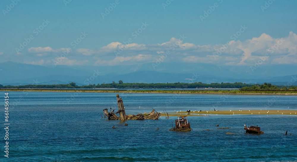 The wrecks of old wooden fishing boats in the shallow waters of the Grado section of the Marano and Grado Lagoon in Friuli-Venezia Giulia, north east Italy. August.