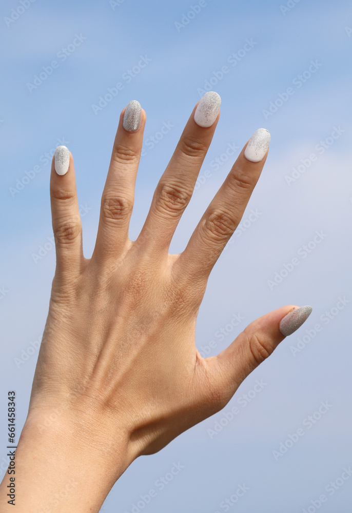 five fingers of the hand with the background of the blue sky and white nail polish five fingers of the hand with the background of the blue sky and white nail polish