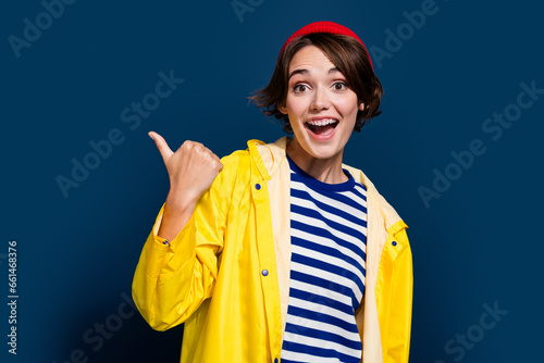 Photo of directing thumb empty space amazed promoter girl hipster walking streets show berghaus store isolated on blue color background photo