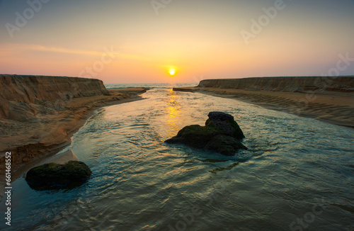 Coastline and sandbanks with tidal waters of Arabian Sea at sunset. Kannur, India.