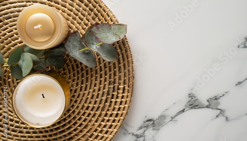 Top view candles on rattan serving mat with eucalyptus on white marble background