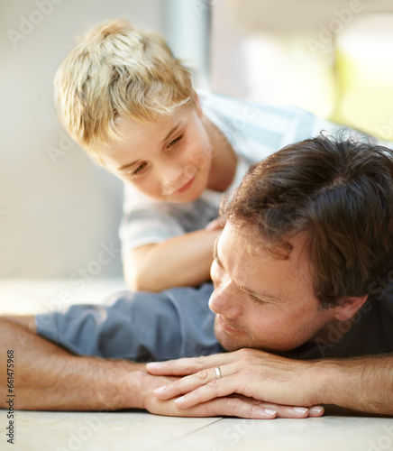 Smile, relax and dad with son on floor, cute bonding together with care and love in home. Fun, father and child lying on ground in house with happy relationship, trust and support with man and boy.
