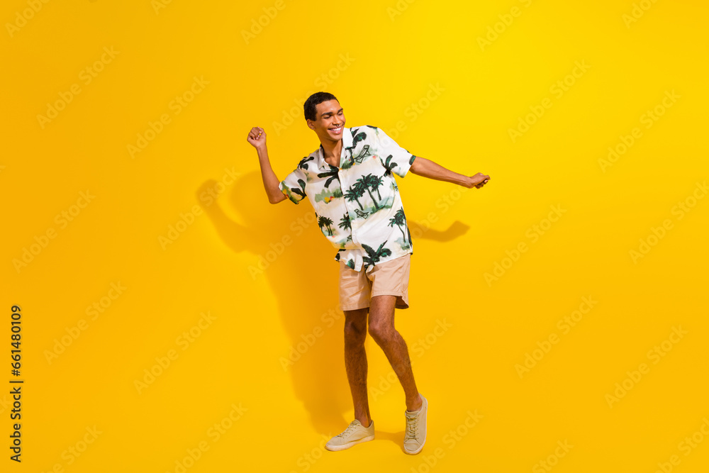 Full size photo of handsome young guy dancing have fun party dressed stylish palms print outfit isolated on yellow color background