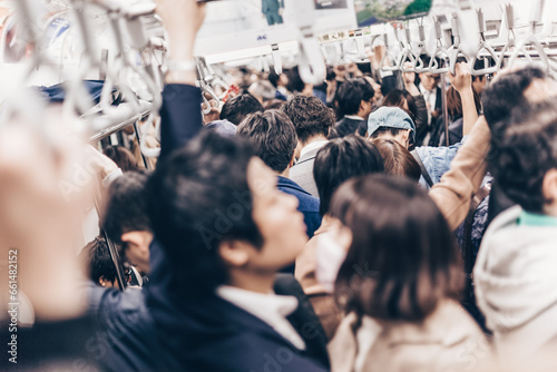 Passengers traveling by Tokyo metro. Business people commuting to work by public transport in rush hour. Shallow depth of field photo. Horizontal composition. photo