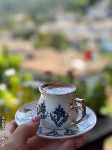 turkish coffee in a traditional porcelain mug and village view at the background