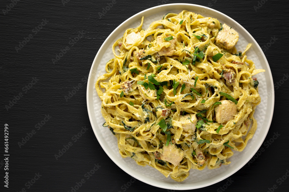 Homemade Creamy Chicken Bacon Pesto Pasta on a Plate on a black background, top view. Flat lay, overhead, from above. Copy space.