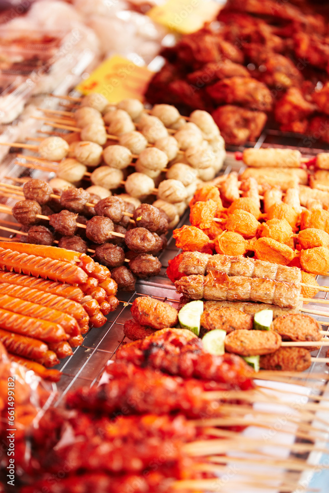 Fototapeta premium Meat, skewers and local market with food sale, shopping and choice for retail or small business background. Seller or entrepreneur with sausage, pork and bbq or chicken stick for restaurant or buffet