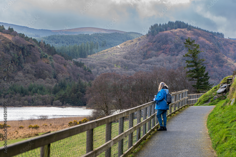 Blond mature women in casual clothing walking on a path by Lower Lake in the Wicklow Mountains