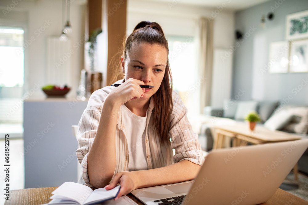 Young woman going over her bills and payments on the laptop at home Young woman going over her bills and payments on the laptop at home