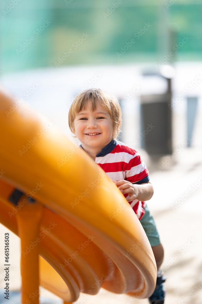 Cute smiling blonde boy climbing up the slide and looking in the camera Cute smiling blonde boy climbing up the slide and looking in the camera