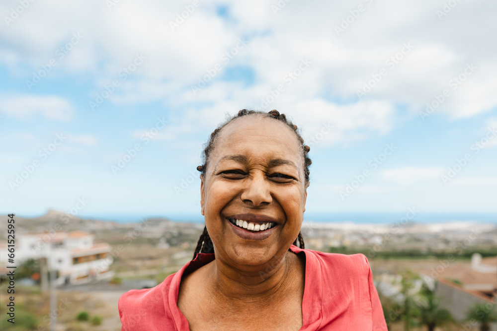 Happy senior African woman having fun smiling into the camera at house rooftop Happy senior African woman having fun smiling into the camera at house rooftop