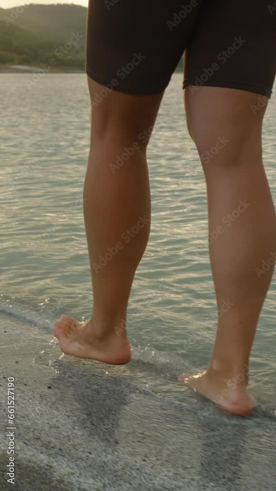 Vertical video. The Last Rays of the Sunset fall on the waters of the Mountain Lake as the bare feet of a Young Woman walk through the water. Vertical video. The Last Rays of the Sunset fall on the waters of the Mountain Lake as the bare feet of a Young Woman walk through the water.