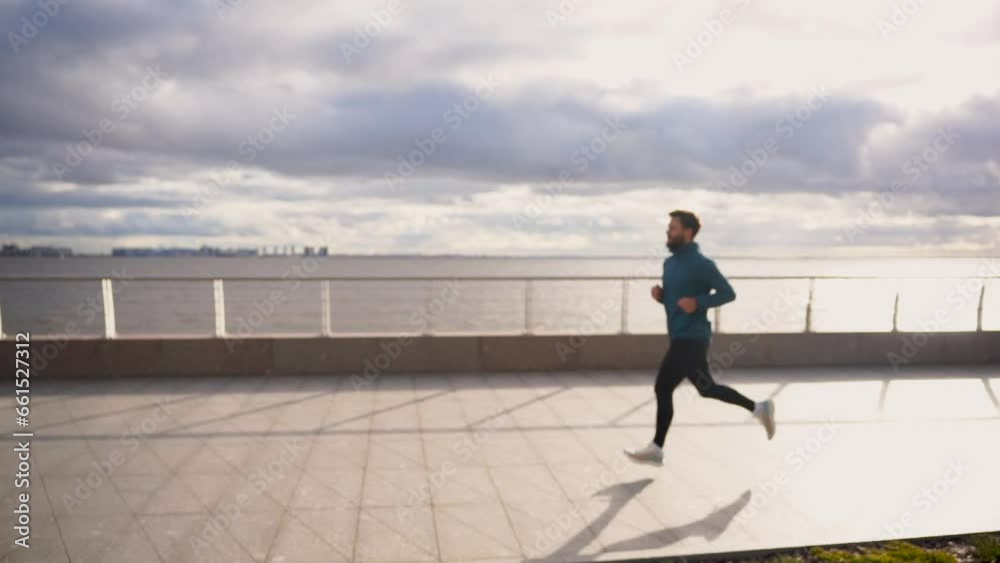 A runner is a sporty man running in running shoes and sportswear. Side view, slow motion. Motivation and mental health for fitness training. An active lifestyle is a sporty person. A runner is a sporty man running in running shoes and sportswear. Side view, slow motion. Motivation and mental health for fitness training. An active lifestyle is a sporty person.