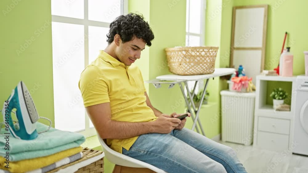 Young latin man playing video game waiting for washing machine at laundry room Young latin man playing video game waiting for washing machine at laundry room