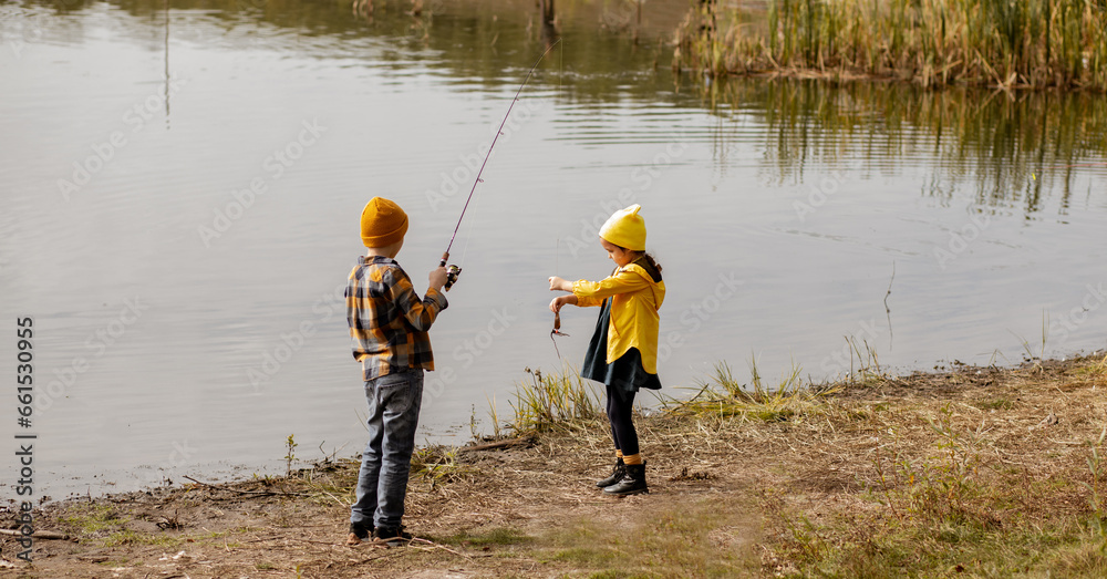 Little cute girl and boy catching a fish in the lake, river or pond.
