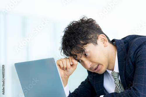 パソコンの画面を見て悩む男性ビジネスマン
