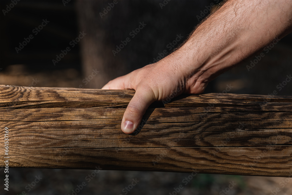 Hand of a middle-aged man holding a wooden log outdoors with natural light. Horizontal photography Hand of a middle-aged man holding a wooden log outdoors with natural light. Horizontal photography
