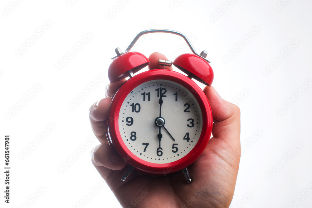 A beautiful red alarm clock in hand shows 6 o'clock in the morning.
Round alarm clock close-up on a white background. A beautiful red alarm clock in hand shows 6 o'clock in the morning.
Round alarm clock close-up on a white background.
