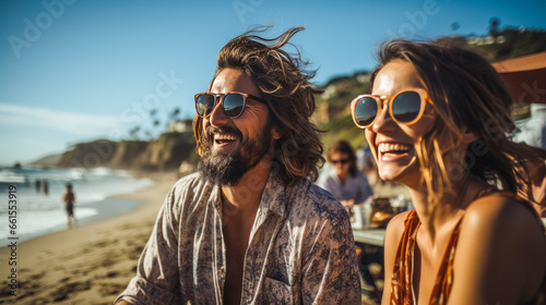 Man in beachwear capturing laughing girlfriend on Californian beach.