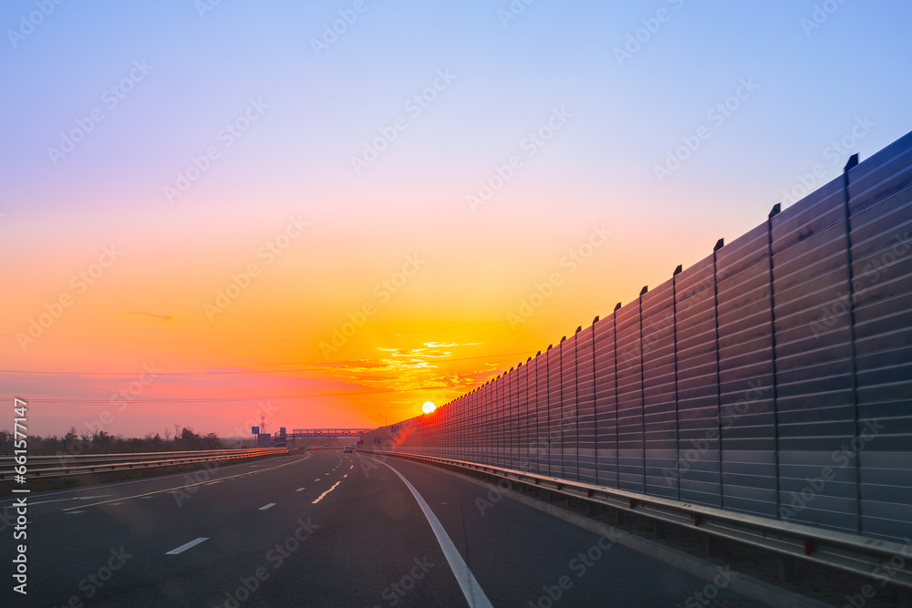 Road with screen noise-reducing wall at dawn