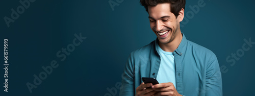 Happy smiling young man using his phone on a colored background. © MP Studio