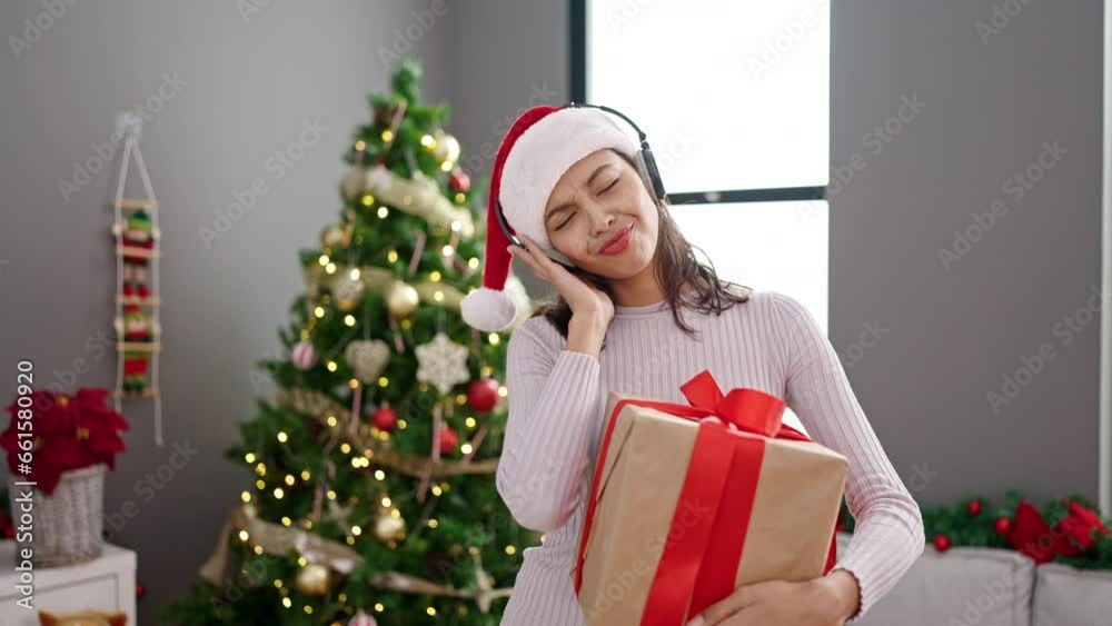 Young beautiful hispanic woman dancing by christmas tree wearing headphones at home Young beautiful hispanic woman dancing by christmas tree wearing headphones at home