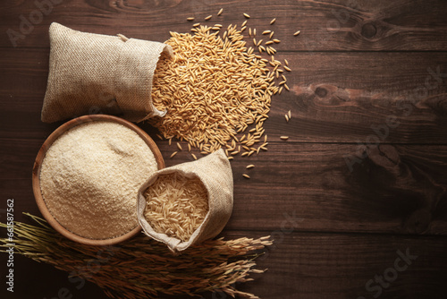 Top view of organic Rice (Oryza sativa) flour in a wooden bowl and raw stages of rice in a jute bag. photo