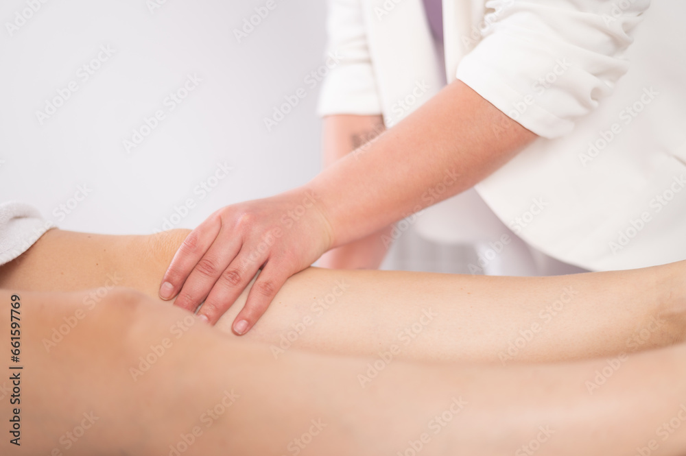Fototapeta premium Crop massage therapist massaging knee of client
