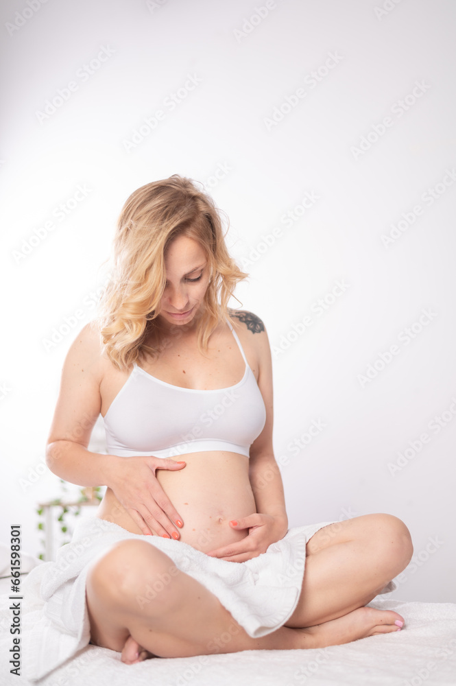 Woman awaiting baby caressing tummy in spa salon Woman awaiting baby caressing tummy in spa salon