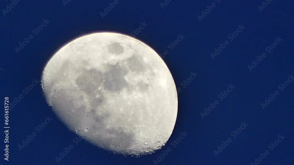 Dark blue sky and silver Moon with visible craters on evening time - real time. Phase of moon as observed from Northern Hemisphere. Topics: space, science, cosmos, atmosphere Dark blue sky and silver Moon with visible craters on evening time - real time. Phase of moon as observed from Northern Hemisphere. Topics: space, science, cosmos, atmosphere