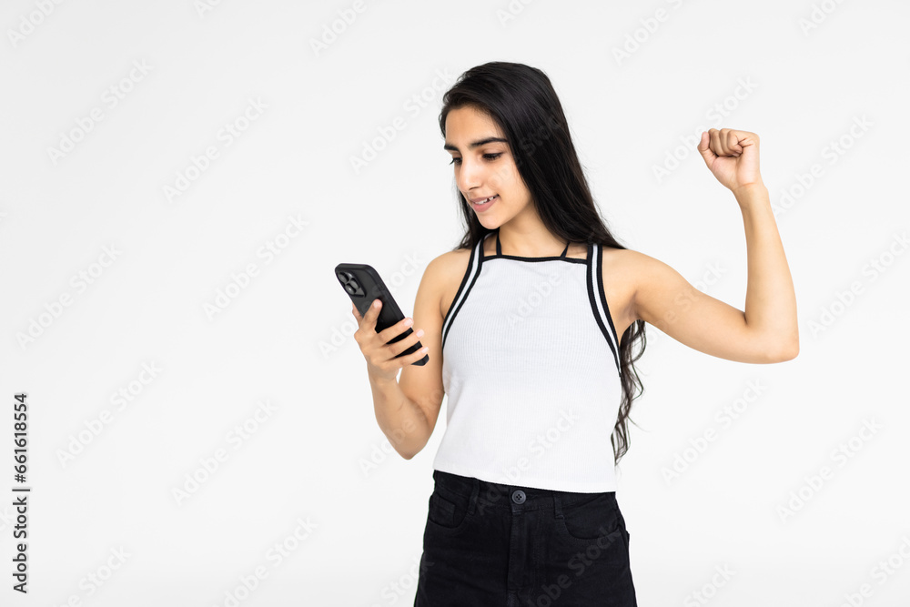 Happy indian young woman great positive surprise, celebrate success on smartphone isolated on white background Happy indian young woman great positive surprise, celebrate success on smartphone isolated on white background