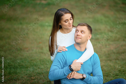 Happy couple in love walking in the park, man holding woman from behind and their eyes meet.