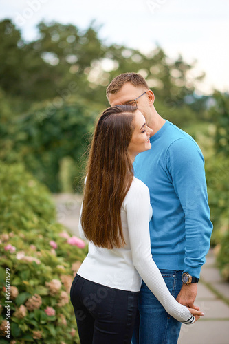Young people holding hands and kissing while walking in the park