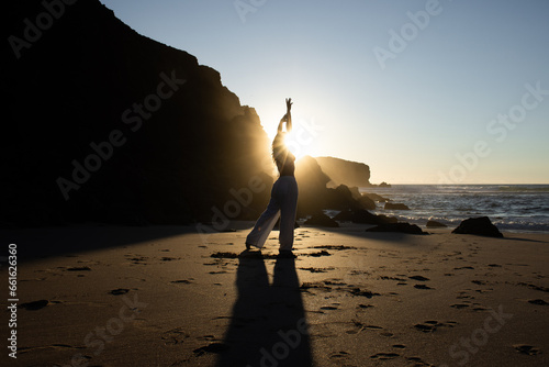 Girl backlit on the beach with sunrise in the background