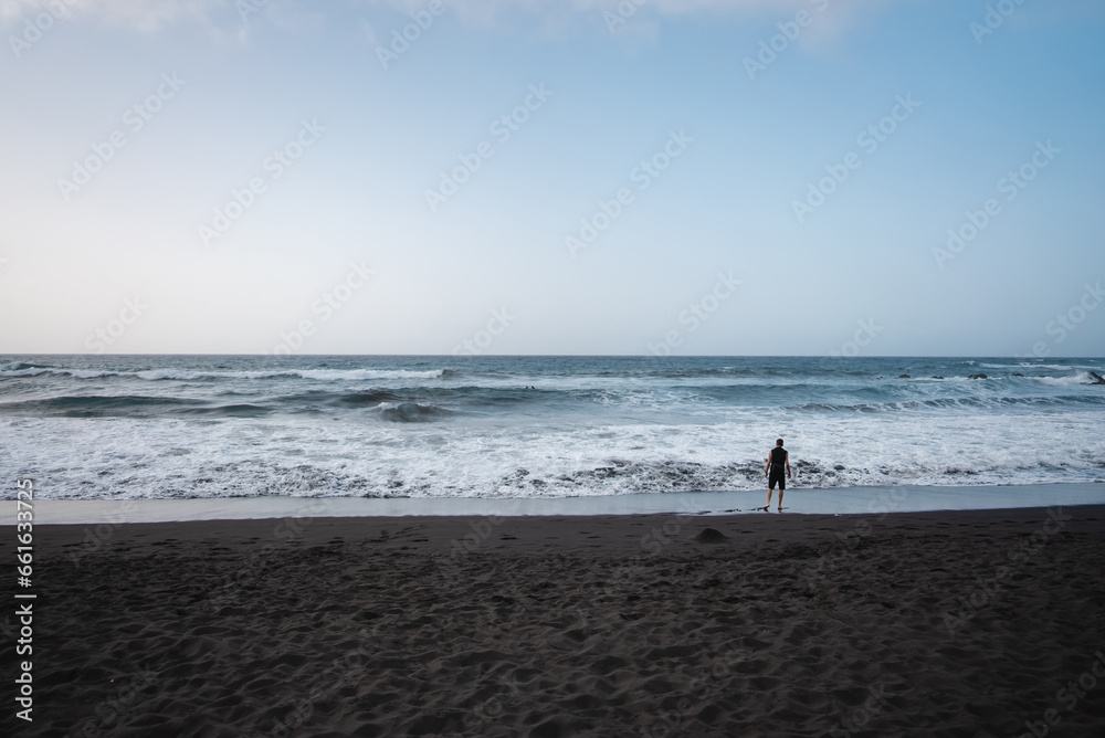 man walking on beach, cloudy weather, beautiful waves of ocean