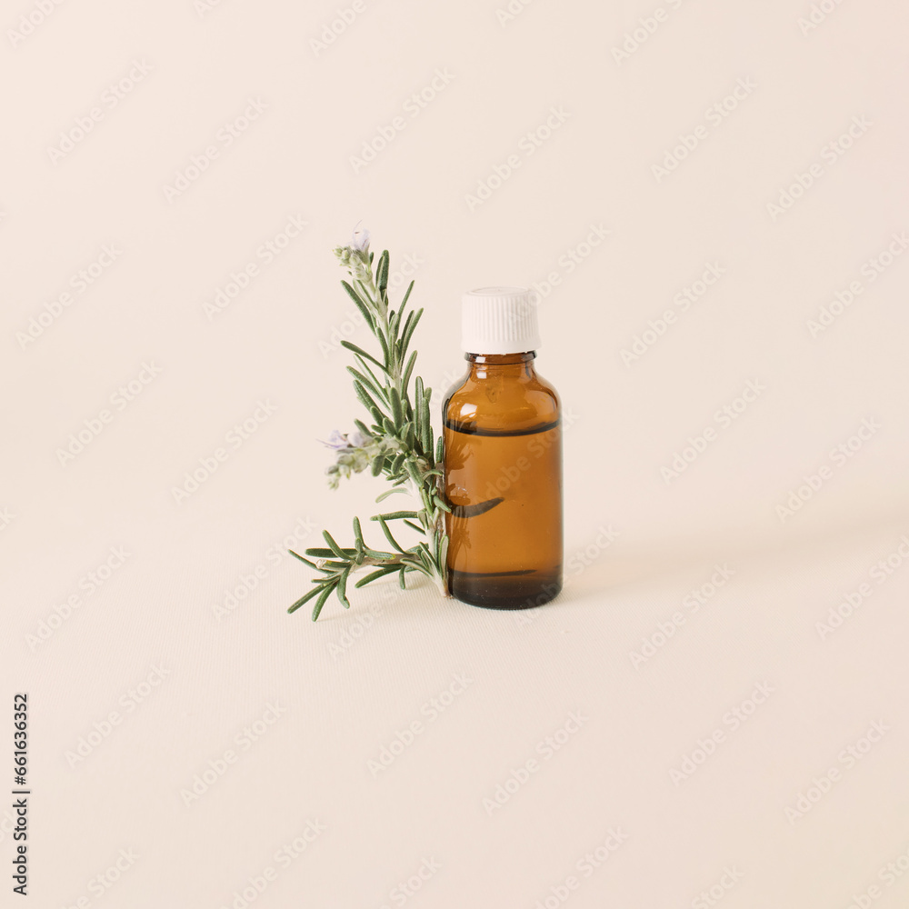 Bottle of essential oil with fresh rosemary twig on a white background. Bottle of essential oil with fresh rosemary twig on a white background.