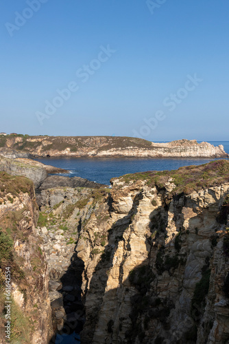 The Rugged Beauty of a Cliffside Coastline Under a Clear Blue Sky © larrui