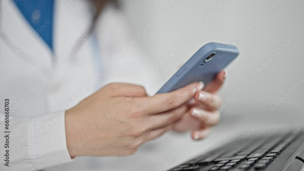 Young beautiful hispanic woman doctor using smartphone sitting on table at the clinic Young beautiful hispanic woman doctor using smartphone sitting on table at the clinic